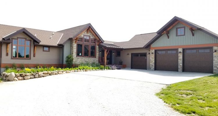 Driveway leading up to timber frame home with extensive landscaping and gardens