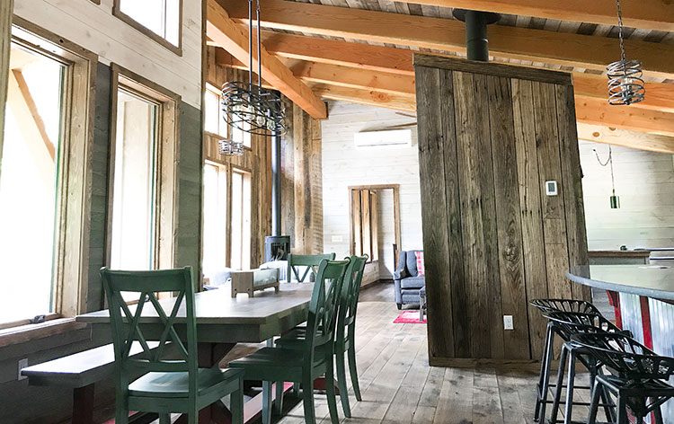 Timber frame great room with exposed rafters and a wall of windows