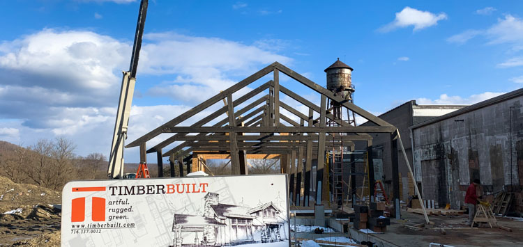 Construction site of large timber frame with a forklift hoisting timbers