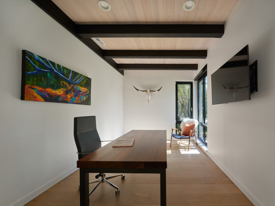 Clean, modern office with wood floors and ceilings, wall mounted television and modern art