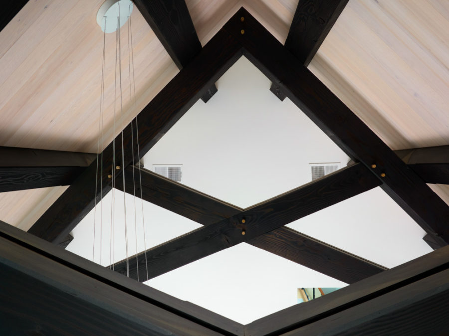 Dark wood timber truss stained black with lighter colored tongue and groove ceiling