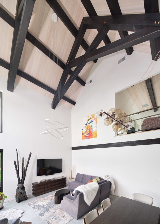 Dark timber truss system on ceiling of white great room with modern decor