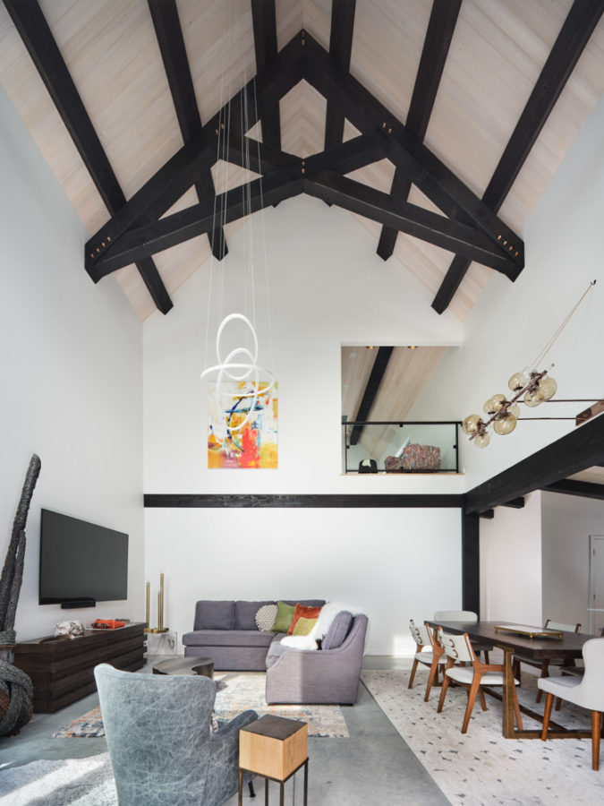 Stark white great room with cathedral ceiling and dark trusses. Modern decor.