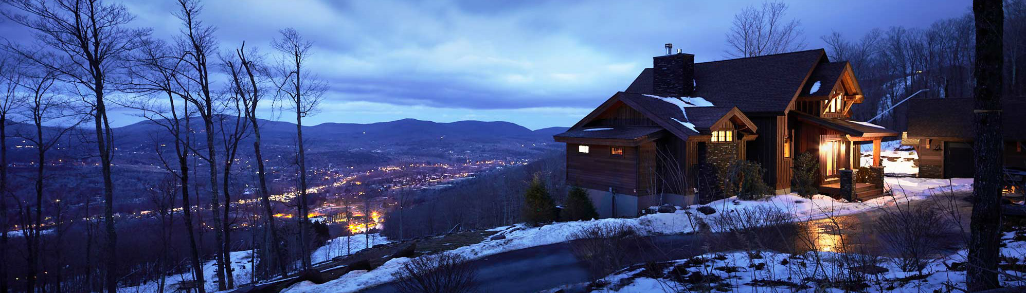 Mountain modern home on hill overlooking mountains just past sunset.